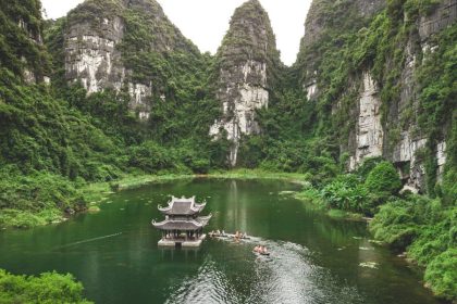 Luxury Vietnam Train travelers exploring Trang An boat route through limestone mountains