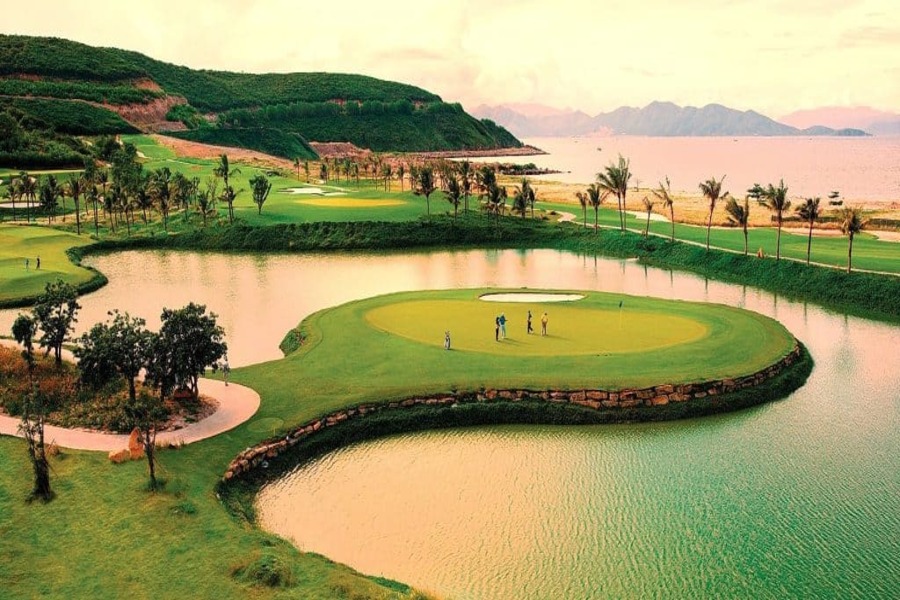Golfers on a coastal green surrounded by water and palm trees