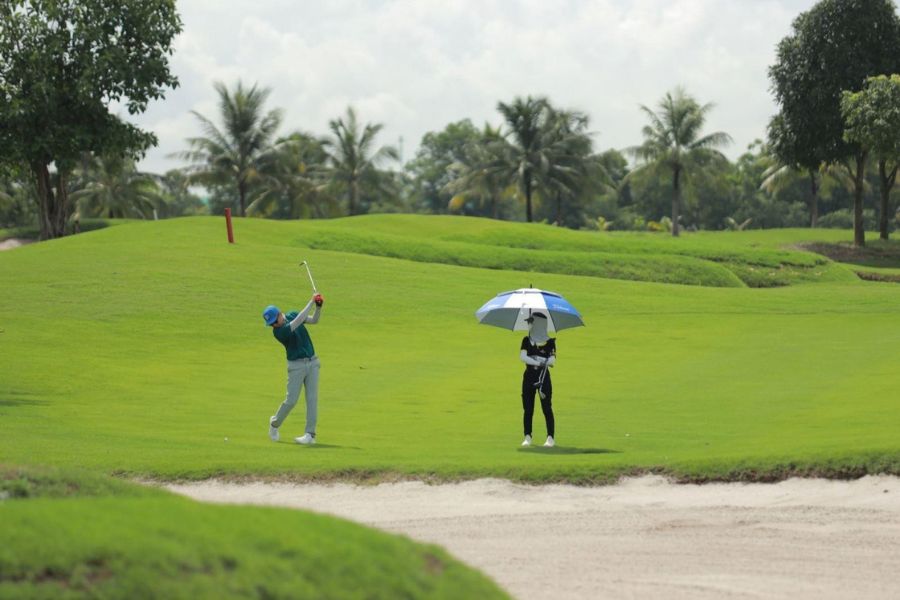 Vietnamese golf caddie assisting a golfer on the course